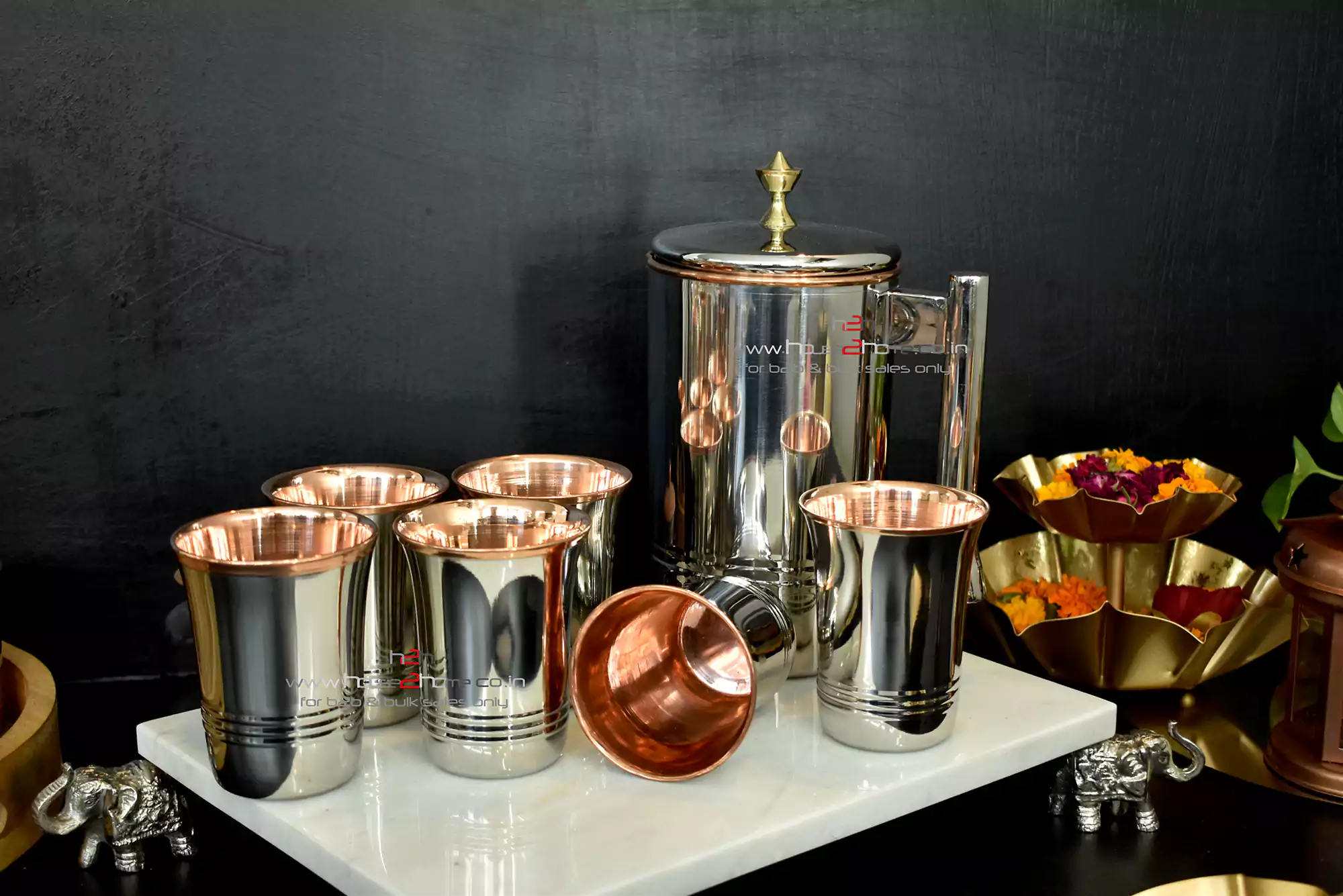 A sleek stainless steel and copper pitcher and tumbler set, displaying premium metallic craft and finish.