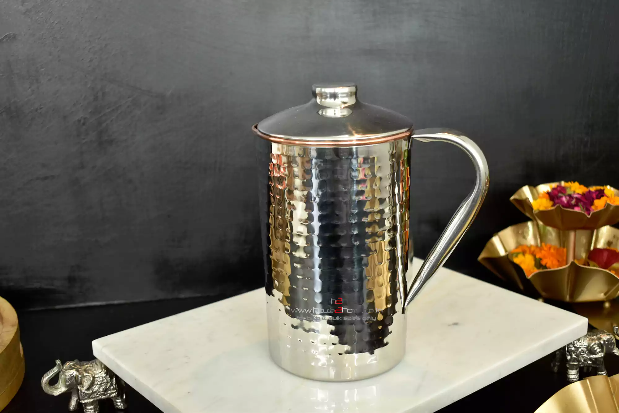 A gleaming, hammered stainless steel pitcher with a lid, offering a refined and durable metallic aesthetic.