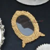 Oval metal photo frame in a rich gold finish with intricate floral embossing for a classic decorative aesthetic.