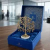An elegant brass-tone metal tree of life decor piece featuring detailed leaves and a marble stand.