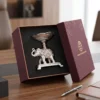 A luxury silver-plated elephant platter figurine supporting a fluted bowl nestled in a dark presentation box.