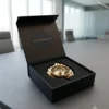 An open black gift box reveals a gleaming gold finish metal leaf diya with a central wick post.