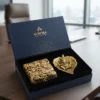 A House2Home gift set featuring a gold-toned Ganesha leaf sculpture and an ornate decorative box arranged neatly inside a branded box.