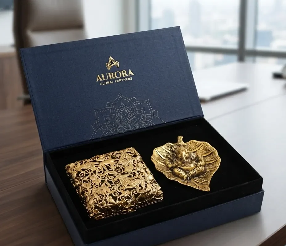 A House2Home gift set featuring a gold-toned Ganesha leaf sculpture and an ornate decorative box arranged neatly inside a branded box.