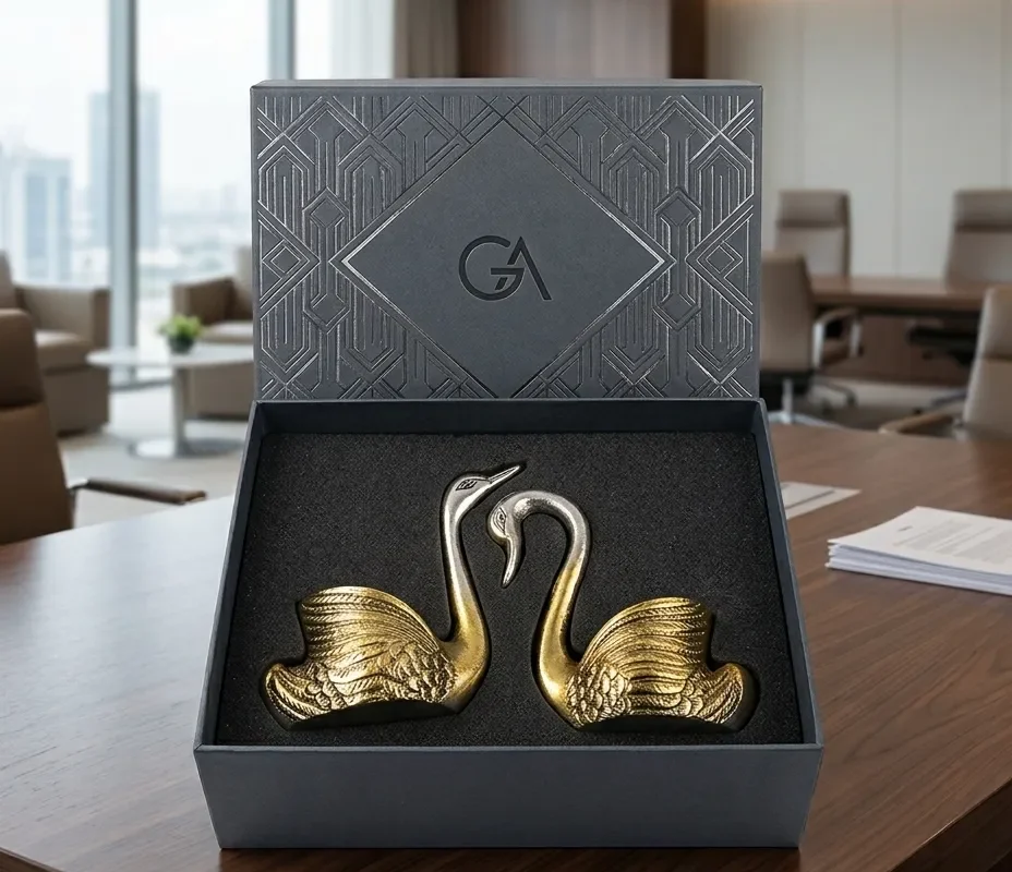 A premium dual-tone metal swan couple figurine set nested in a custom luxury presentation box.