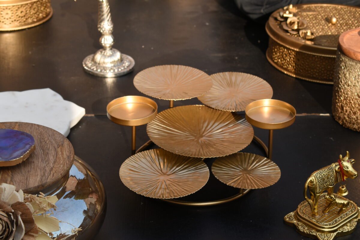 A decorative candle display stand with a polished gold metallic coating designed by House2Home.