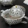 decorative silver metal bowl with elaborate cutout side handles, resting on small feet for elegance.