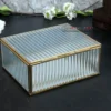 A rectangular decorative storage box with a gold metal frame and clear textured glass design on display.