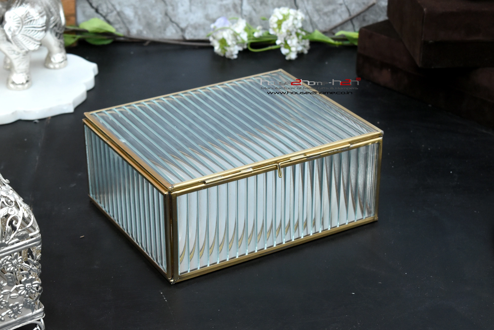A rectangular decorative storage box with a gold metal frame and clear textured glass design on display.