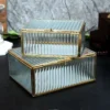An exquisite glass and metal organiser box featuring a gold-toned frame and vertical ribbed glass texture.