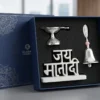 A German silver ritual set featuring a traditional diya, a decorative bell, and Jay Mata Di script in a gift box.