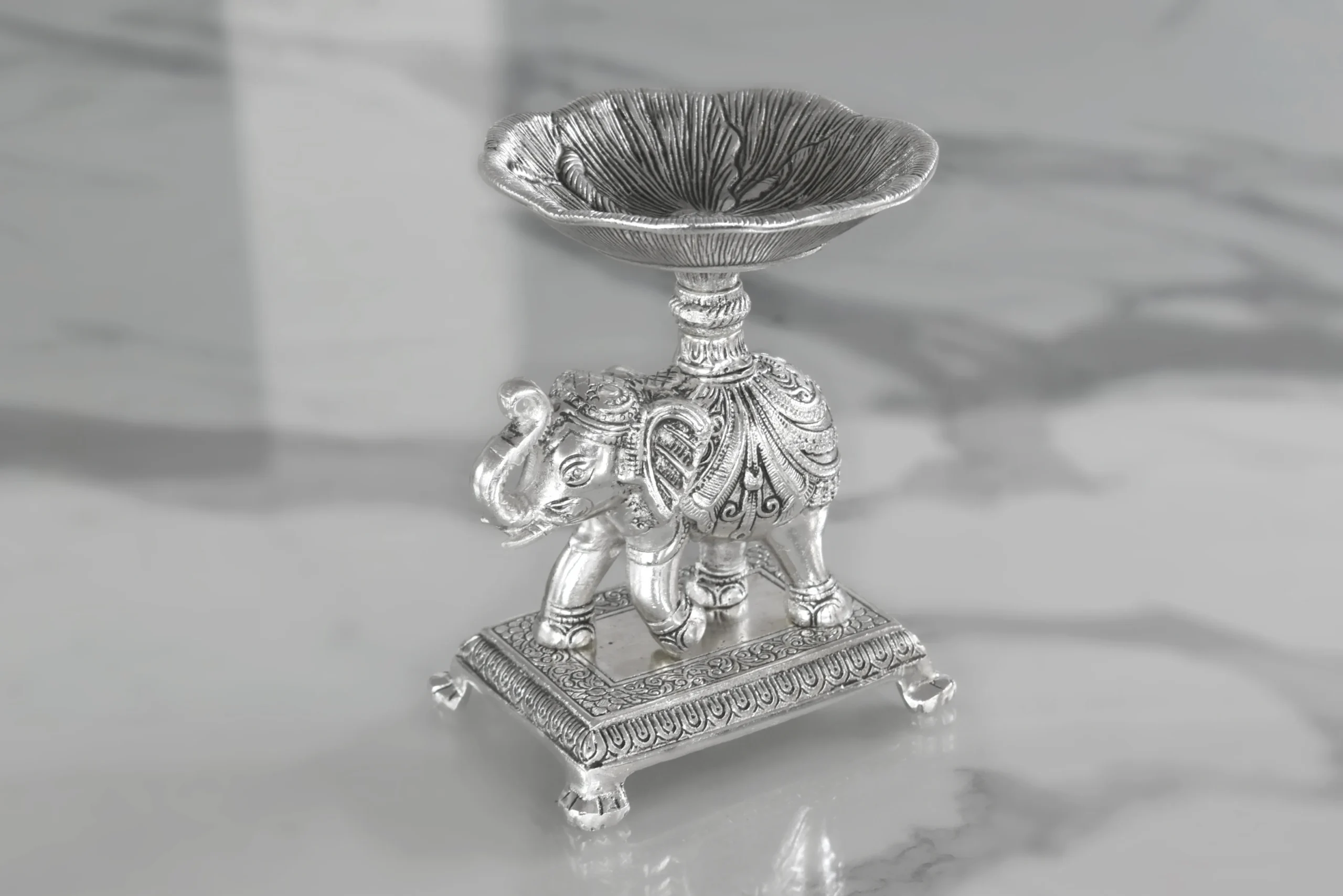 Silver elephant bowl stand styled as an auspicious wedding return gift favor for luxury shaadi hampers.
