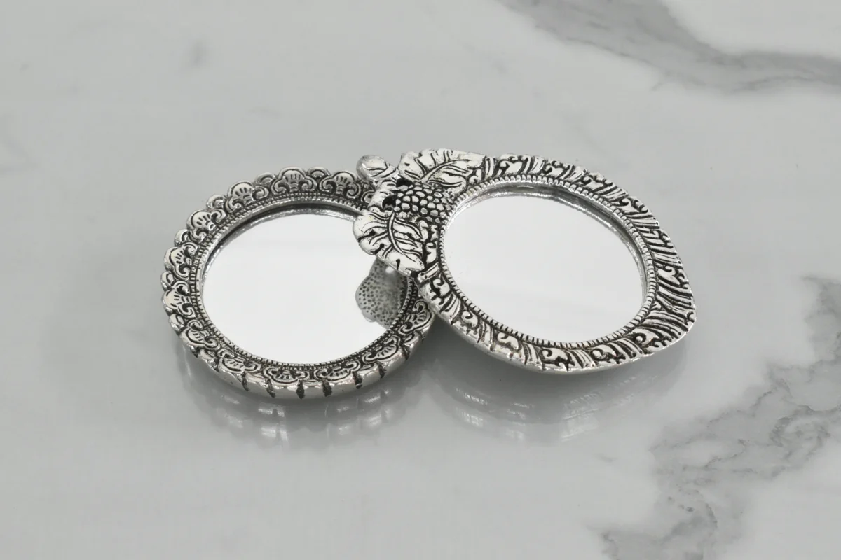 Silver-plated embossed metal pocket mirrors with ornate frames for traditional dressing and vanity decor.
