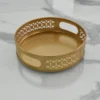 Round gold metal decorative tray with integrated cut-out handles for home styling and display.