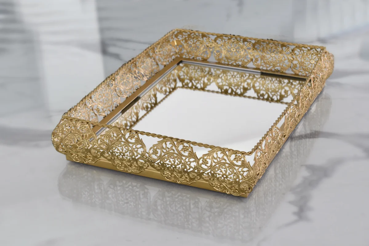 Gold-finished filigree metal tray with mirrored base for elegant home decor and gifting displays.