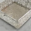 Silver-plated open metal basket with intricate filigree walls and embossed base for luxury decor.