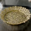Gold-finished filigree metal round tray with intricate lace border and glass base for home styling.