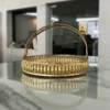 Round decorative brass basket featuring an elegant arched handle and intricate metal cutwork body detailing.